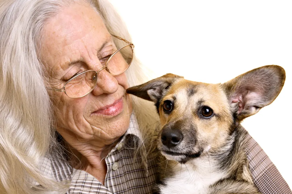 An older woman rests her cheek against her dog’s
