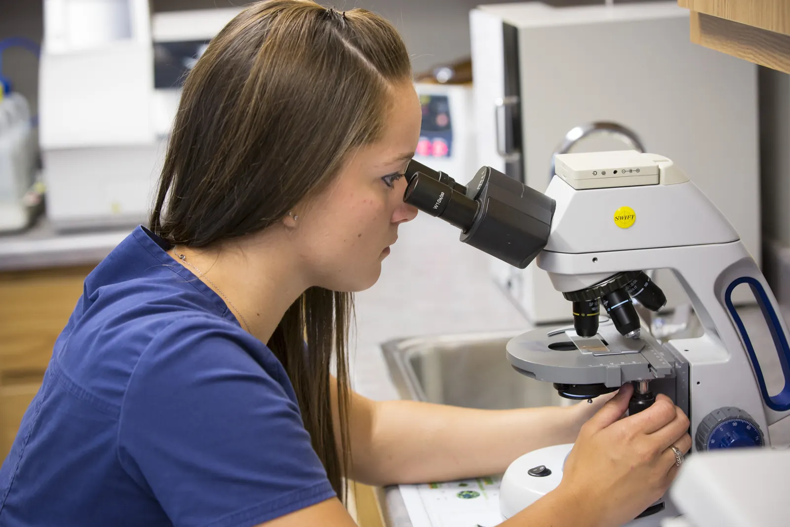 A Countrycare technician looks through a microscope in the clinic’s lab