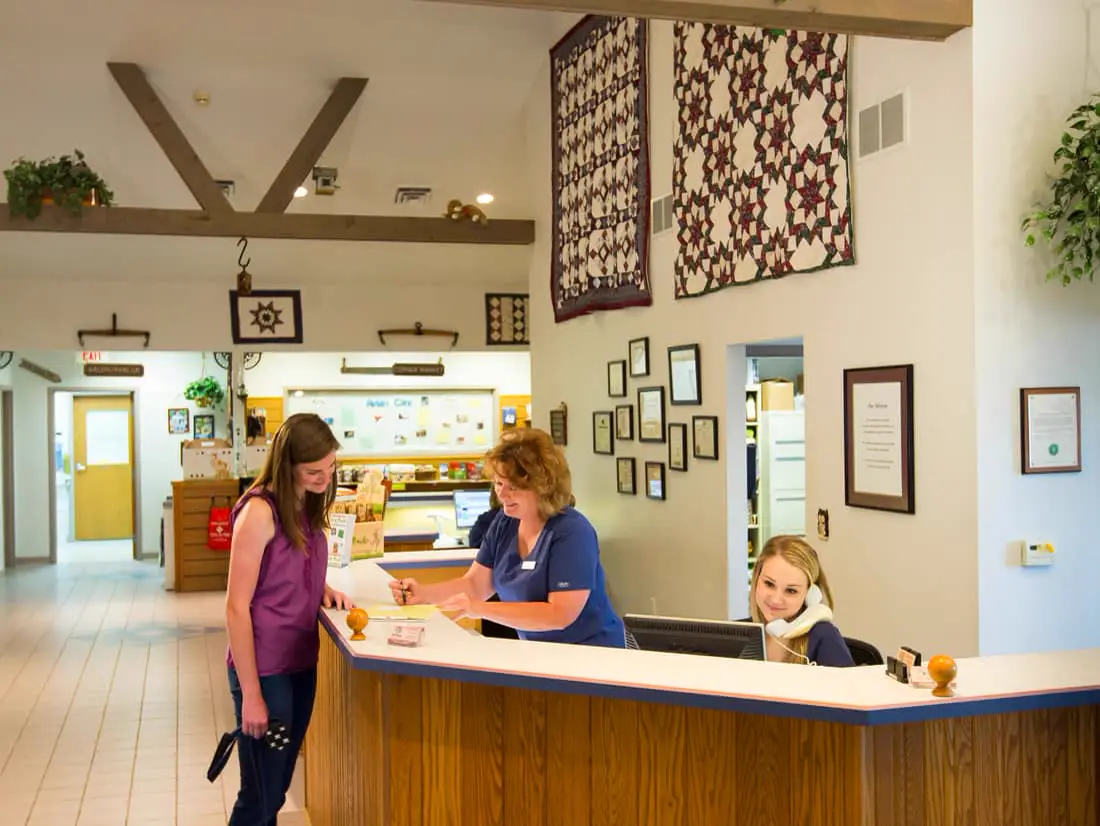 The Countrycare reception desk, with a staff member greeting a client and her dog.